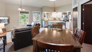 Un comedor espacioso con una mesa y sillas de madera, un sofá y una cocina al fondo.