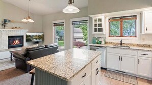 Una cocina moderna con una isla central, muebles blancos y una chimenea.