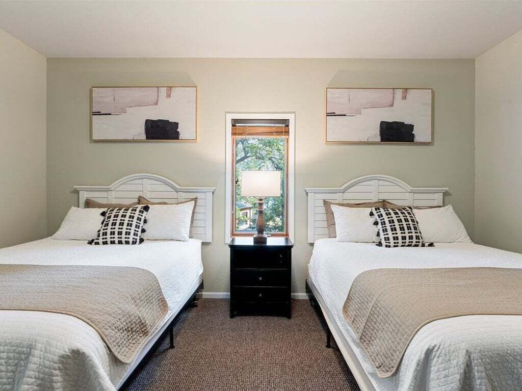 Une chambre avec deux lits, une table de chevet et une fenêtre.