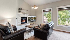 Una sala de estar con chimenea, dos sofás de cuero negro, una mesa de centro y un televisor.