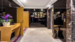 Un corridoio con una reception, quadri alle pareti e pavimento rivestito di moquette.