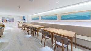 Un interior moderno con una larga barra, zona de estar y una obra de arte en la pared.