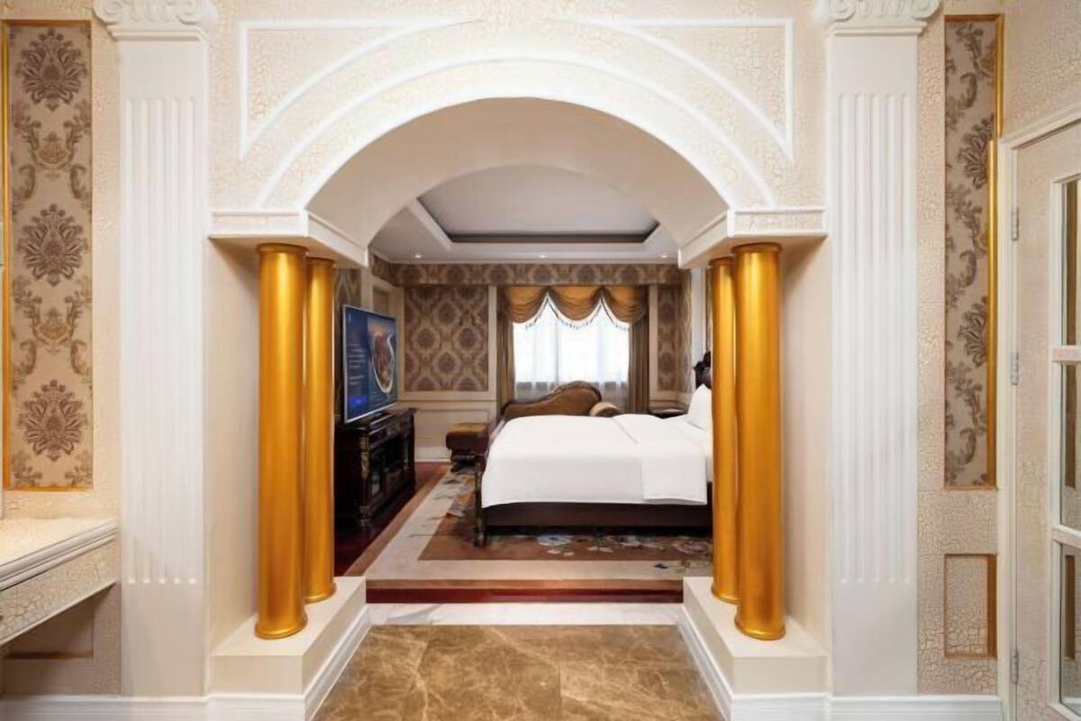 A hotel room with a bed, a television, and a desk.