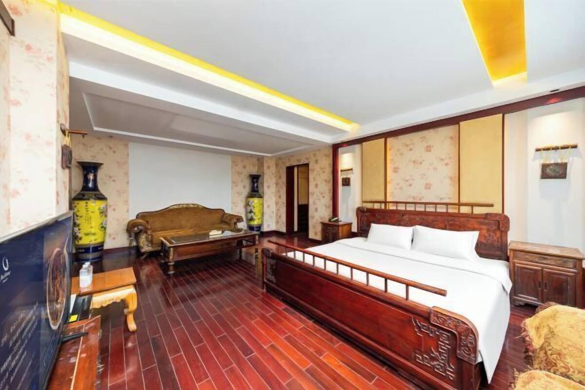 A traditional room with a wooden bed, a sofa, a small table, and a decorative vase.