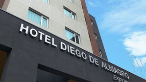 Un edificio alto de hotel con el nombre "HOTEL DIEGO DE ALMAGRO Express" en la fachada.