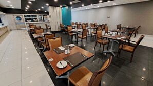 Un restaurante con varias mesas y sillas, una barra con un menú y vistas a la ciudad a través de una ventana.