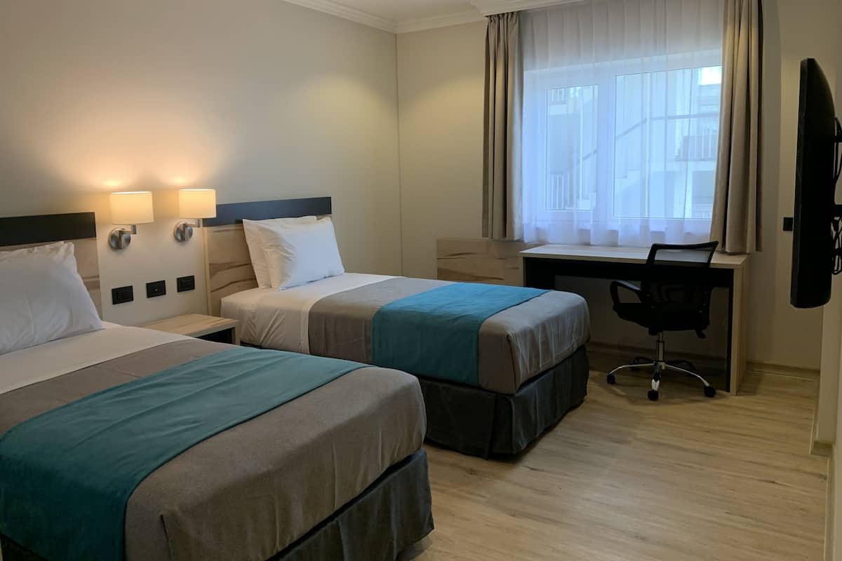 Habitación de hotel con dos camas, un escritorio y una silla.