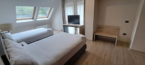 Une chambre avec deux lits, une télévision, un bureau et une fenêtre.