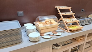 Montaje de bufé con platos, cubiertos, pan y una cesta de pan.