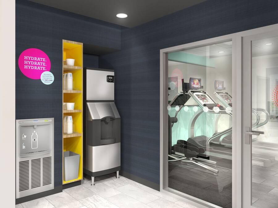 Una habitación moderna y bien iluminada con cafetera, refrigerador y puerta de vidrio que da a una zona de estar.