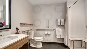 A modern bathroom with a sink, toilet, shower, and a handrail.