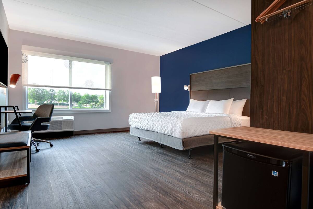 Une chambre d’hôtel équipée d’un lit, d’un bureau, d’une chaise et d’un petit réfrigérateur.
