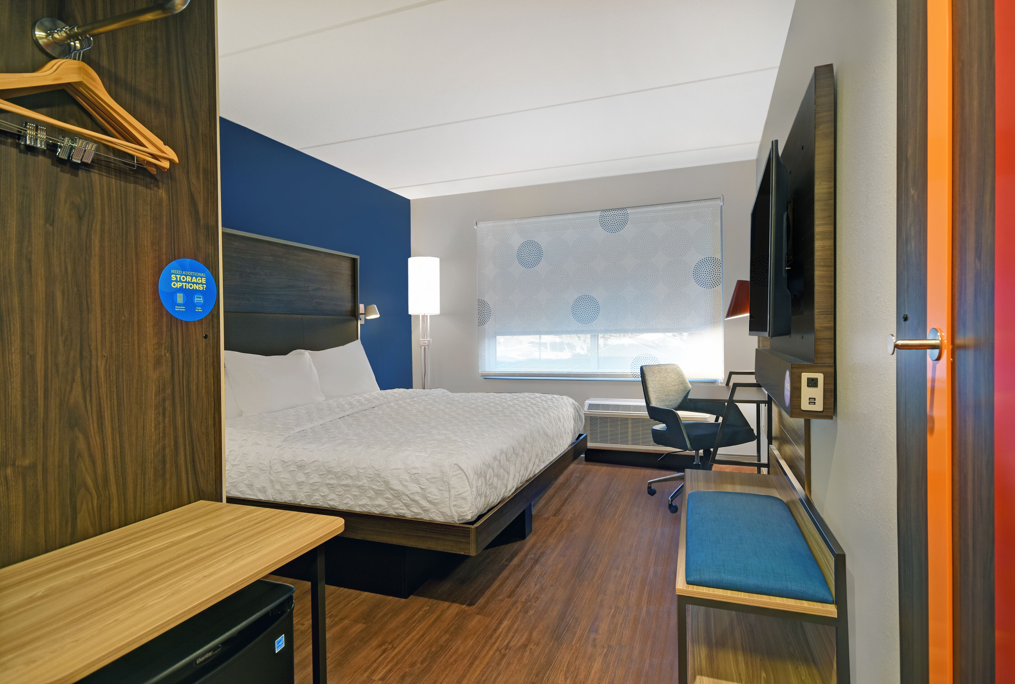 Una habitación de hotel pequeña con cama, escritorio, silla y televisión.