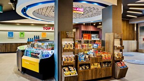 A food kiosk with a variety of snacks and beverages, a sign for a 24/7 market, and a 'Top It' sign in the background. - Tru by Hilton Franklin Cool Springs Nashville (Franklin)