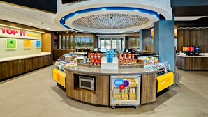 A breakfast area with a counter displaying various food items and a refrigerator stocked with beverages. - Tru by Hilton Franklin Cool Springs Nashville (Franklin)