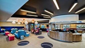 A modern lobby with seating areas, a reception desk, and a large window offering a view. - Tru by Hilton Franklin Cool Springs Nashville (Franklin)