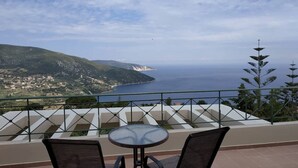 A balcony with a round table and two chairs, overlooking a coastal landscape with a view of the sea and distant hills. - Villa "Sofia" with an amazing view at Angonas. (Agκona)