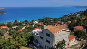 A coastal residential area with houses featuring red-tiled roofs, surrounded by greenery and overlooking the sea. - Villa "Sofia" with an amazing view at Angonas. (Agκona)