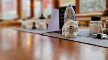 A wooden table with a ceramic rabbit figurine, salt and pepper shakers, and a menu board in a restaurant setting.