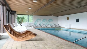 A swimming pool area with lounge chairs and a wooden bench.