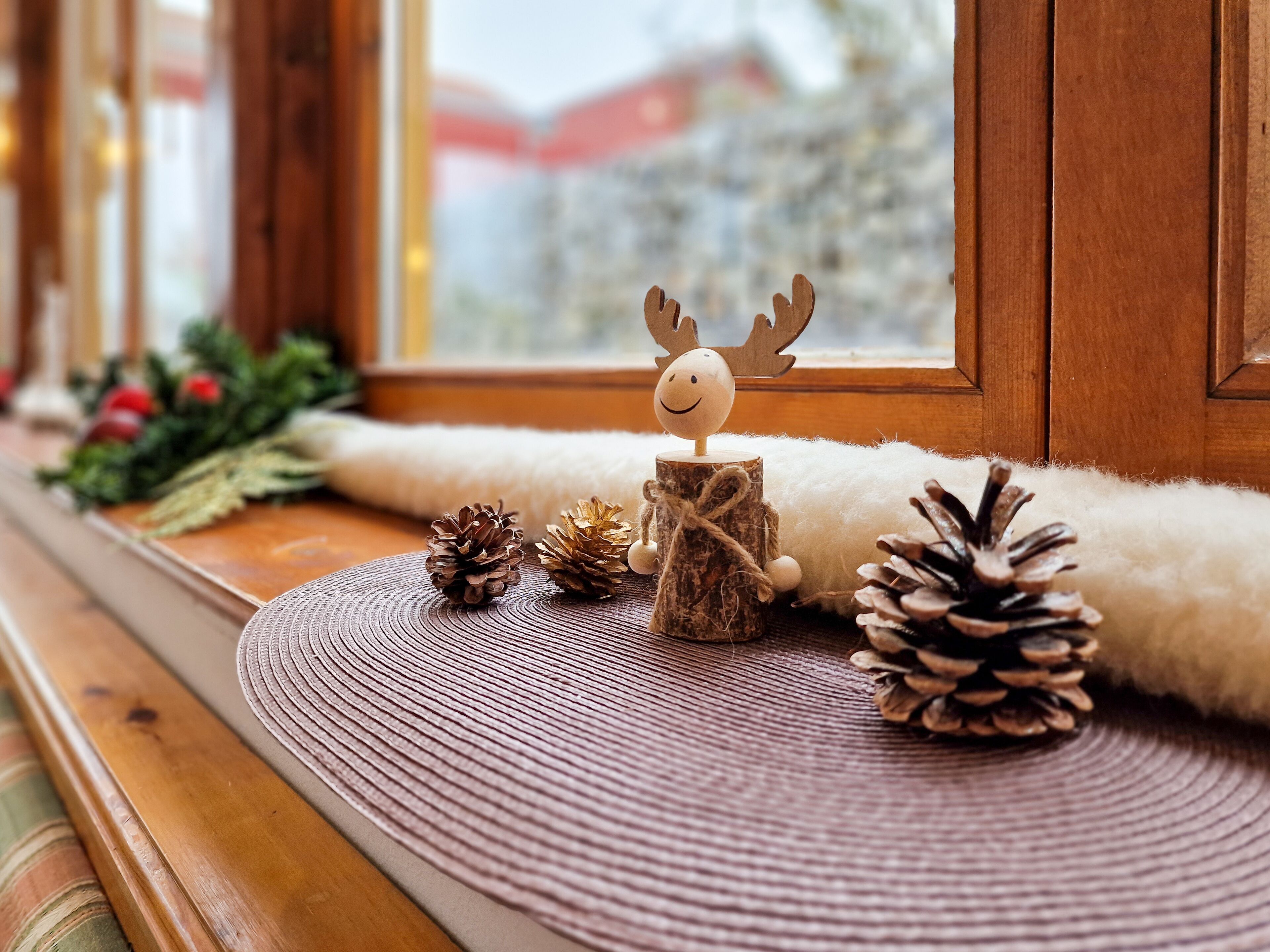 Un interior acogedor con un alféizar de madera, piñas y una decoración de reno.