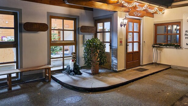 A hotel lobby with a wooden bench, a Christmas tree, and a potted plant.