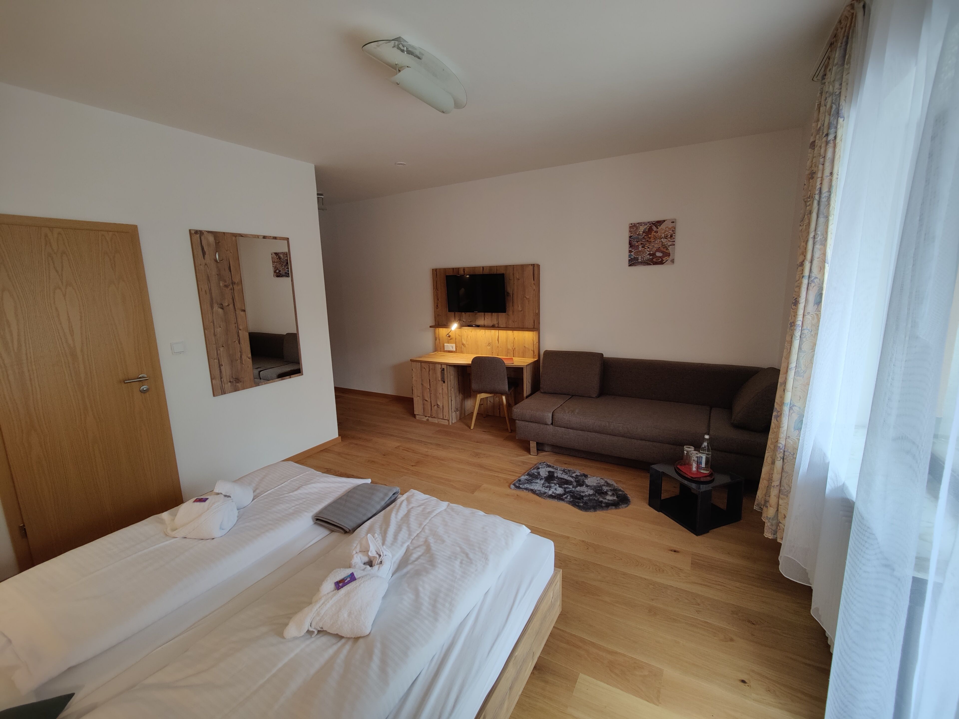 Una habitación de hotel con cama, escritorio, sofá y televisor.