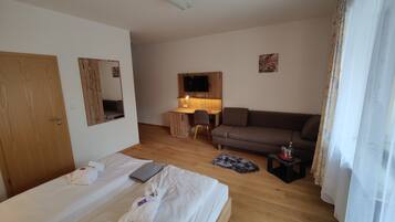 Una habitación de hotel con cama, escritorio, sofá y televisor.