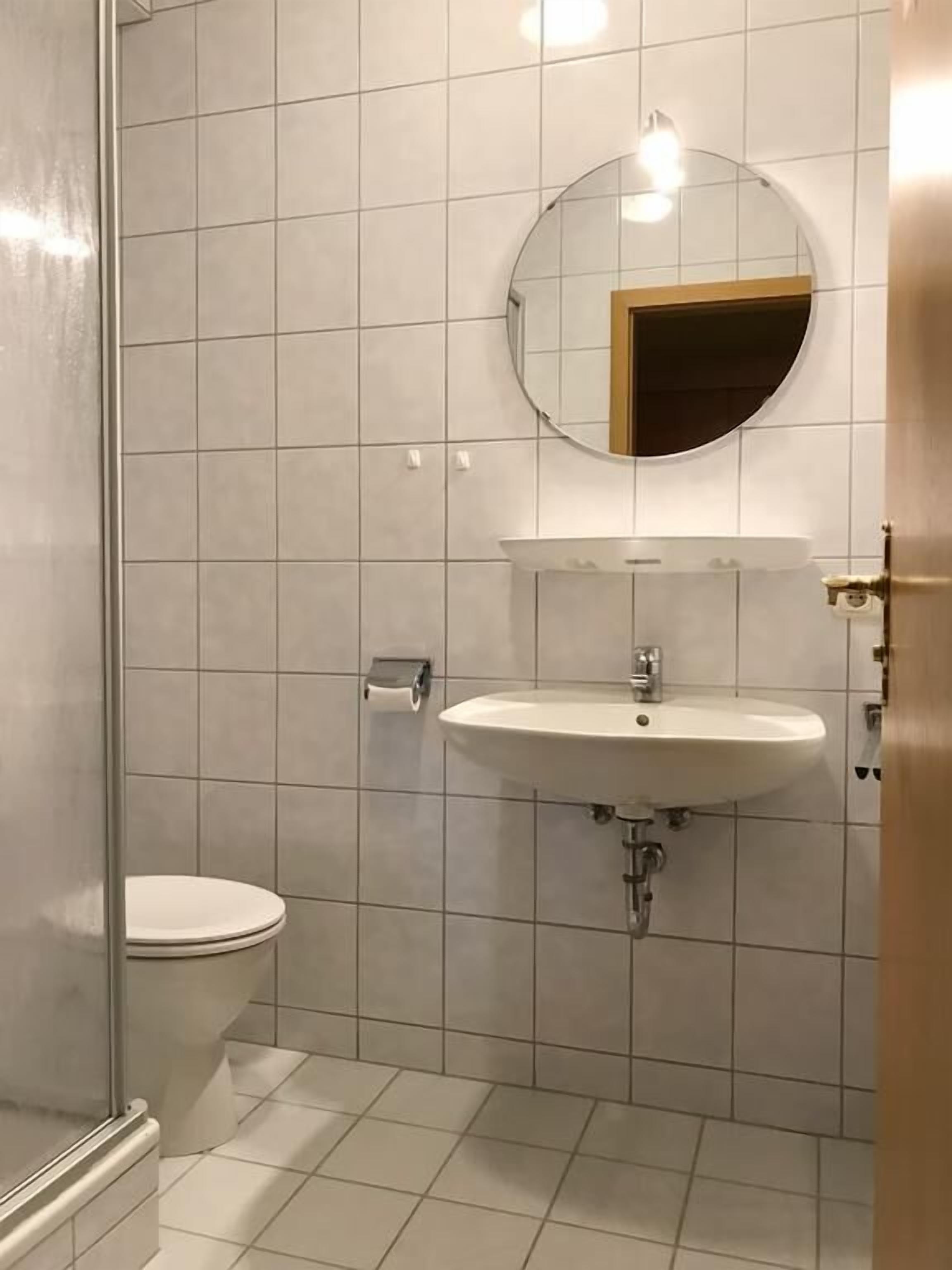Een badkamer met een toilet, een wastafel en een spiegel.