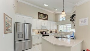 Una cocina moderna con armarios blancos, electrodomésticos de acero inoxidable y una isla grande con un fregadero.