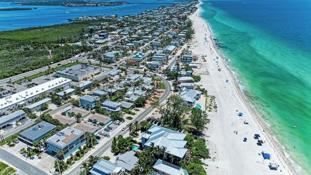 Vista aérea de una zona residencial costera con playa, casas y una carretera.