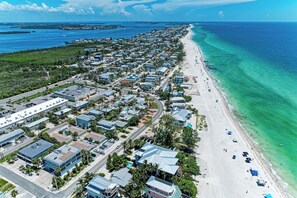 A coastal residential area with beachfront properties, roads, and a clear view of the ocean.