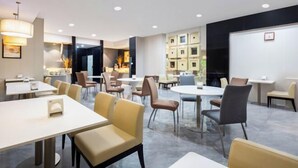 A modern hotel lobby with round tables and chairs, a reception area, and a whiteboard on the wall. - Jinjiang Inn (Weihai High-speed Railway North Station Oulefang Commercial Street Hotel) (Weihai)