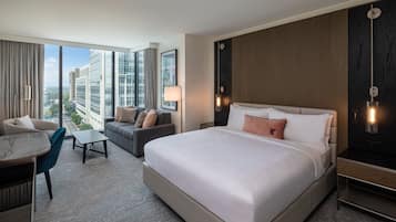 A modern hotel room with a large bed, a sofa, a desk, and a view of the cityscape.