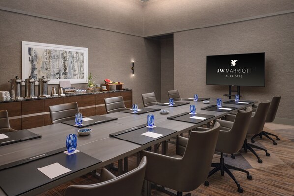 A conference room with a long table, chairs, a TV screen, and a coffee station. - JW Marriott Charlotte (Charlotte)