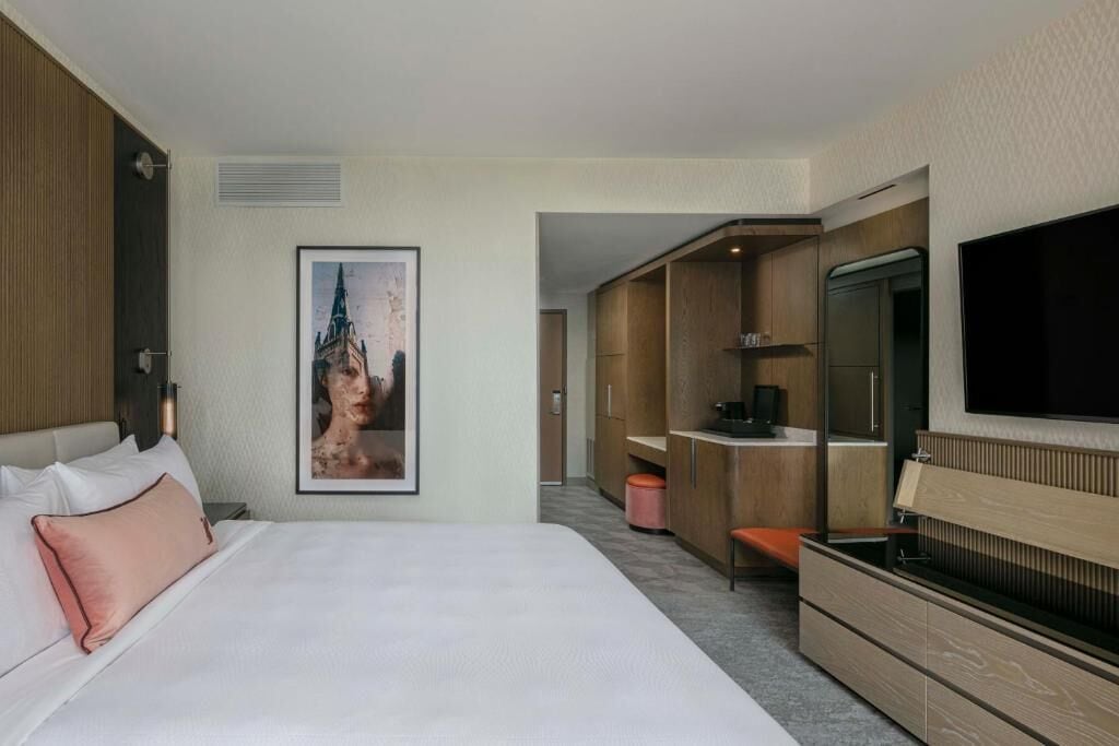 Une chambre d’hôtel avec un grand lit, un bureau, une télévision et une armoire.