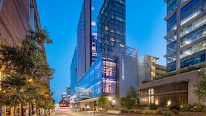 A modern hotel with a prominent glass facade, a JW Marriott logo, and a well-lit urban street scene. - JW Marriott Charlotte (Charlotte)