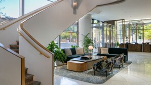 A modern interior with a staircase, a seating area with a coffee table, and large windows offering a view of the outdoors. - JW Marriott Charlotte (Charlotte)