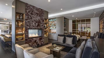 Een moderne woonkamer met een open haard, een zithoek en een keuken op de achtergrond.