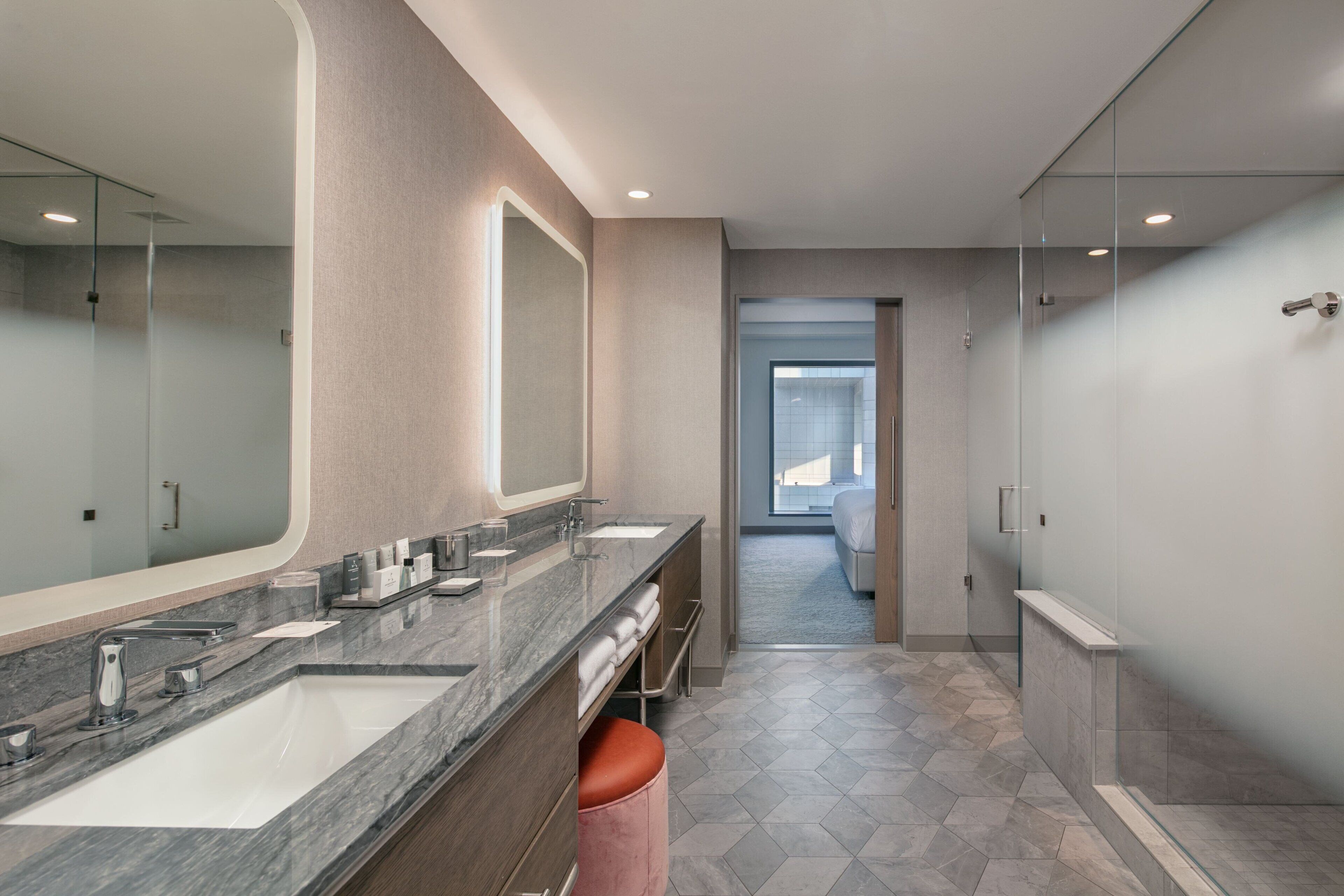 A modern bathroom with two sinks, a large mirror, and a glass shower enclosure.