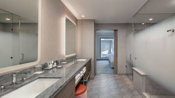 A modern bathroom with two sinks, a large mirror, and a glass shower enclosure.