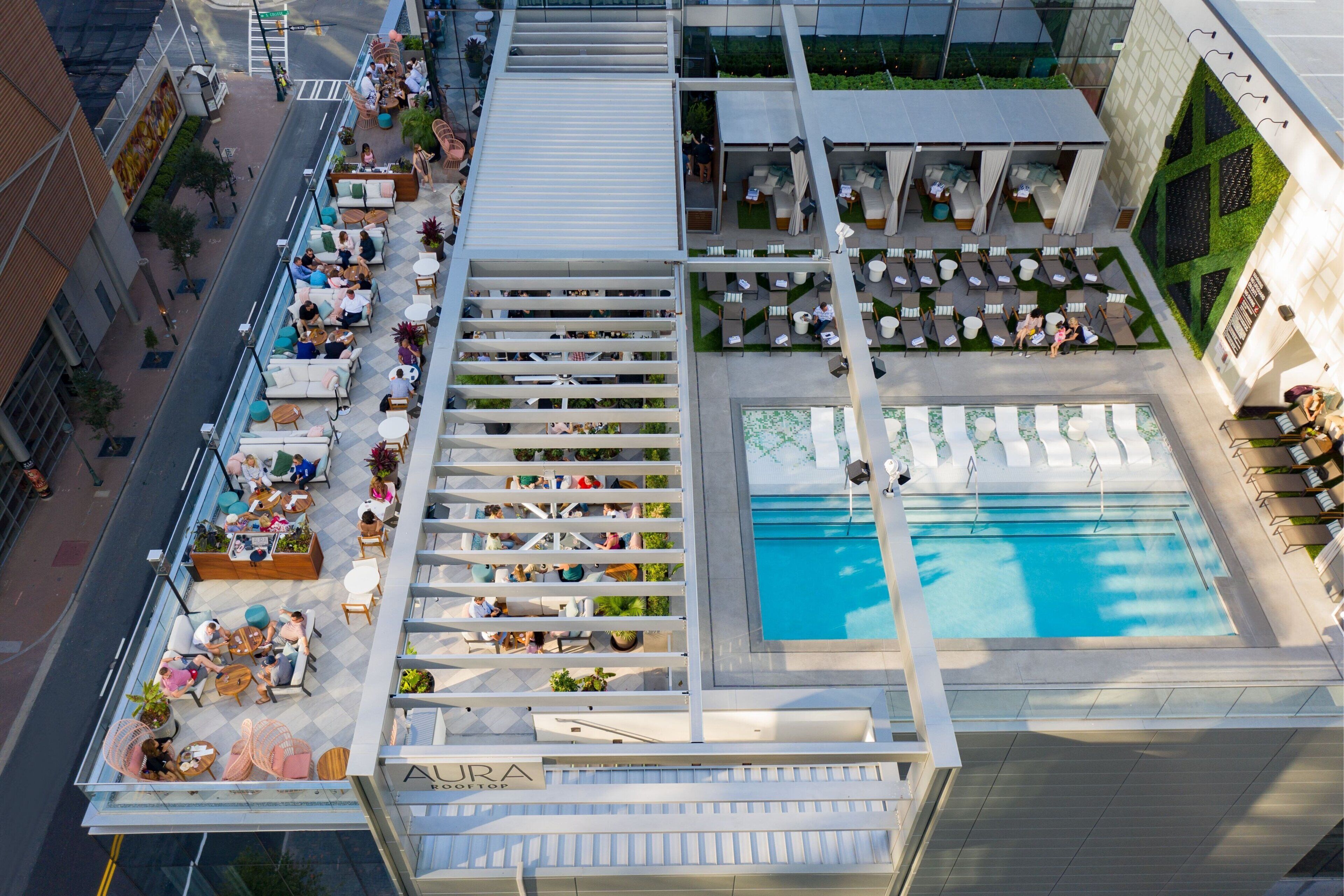 An aerial view of a hotel with outdoor seating areas, a swimming pool, and a rooftop terrace.