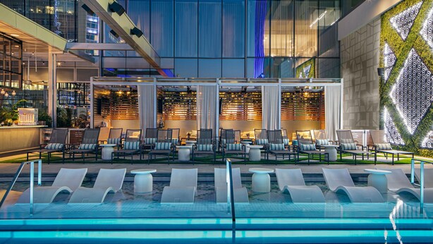 A modern indoor pool area with lounge chairs and a seating area with tables. - JW Marriott Charlotte (Charlotte)