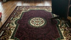 A room with a red sofa, a patterned rug, and a ceiling fan. - Historic Commercial Hotel(Est. 1868)Tom Mix Suite (Osceola)