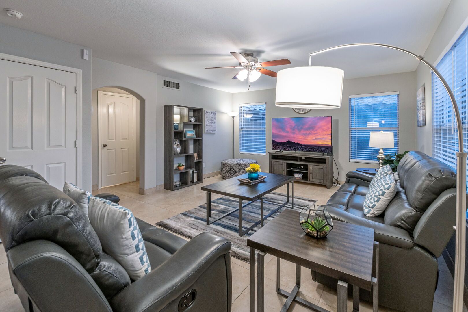 A modern living room with leather sofas, a coffee table, a TV, and a bookshelf.