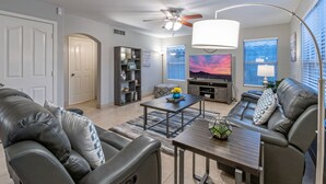 A modern living room with leather sofas, a coffee table, a TV, and a bookshelf. - WOW! Hikers/Bikers/Golfers PARADISE, Pvt Htd POOL, Putt Green, Tesla Charger (Gilbert)