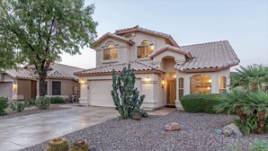 A two-story house with a tiled roof, a driveway, and a landscaped garden with cacti and shrubs. - WOW! Hikers/Bikers/Golfers PARADISE, Pvt Htd POOL, Putt Green, Tesla Charger (Gilbert)