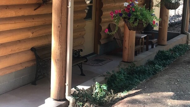 A log cabin with a covered porch, outdoor seating, and hanging flower baskets. - Beautiful bunkhouse in forest just hours outside Phoenix metro area (Strawberry)