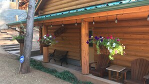 A wooden cabin with a porch, outdoor seating, and hanging flower baskets. - Beautiful bunkhouse in forest just hours outside Phoenix metro area (Strawberry)