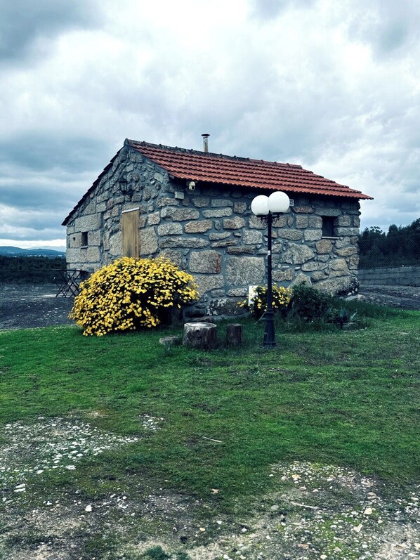 Ein Steinhaus mit rotem Ziegeldach, einer Holztür und einem kleinen Fenster.